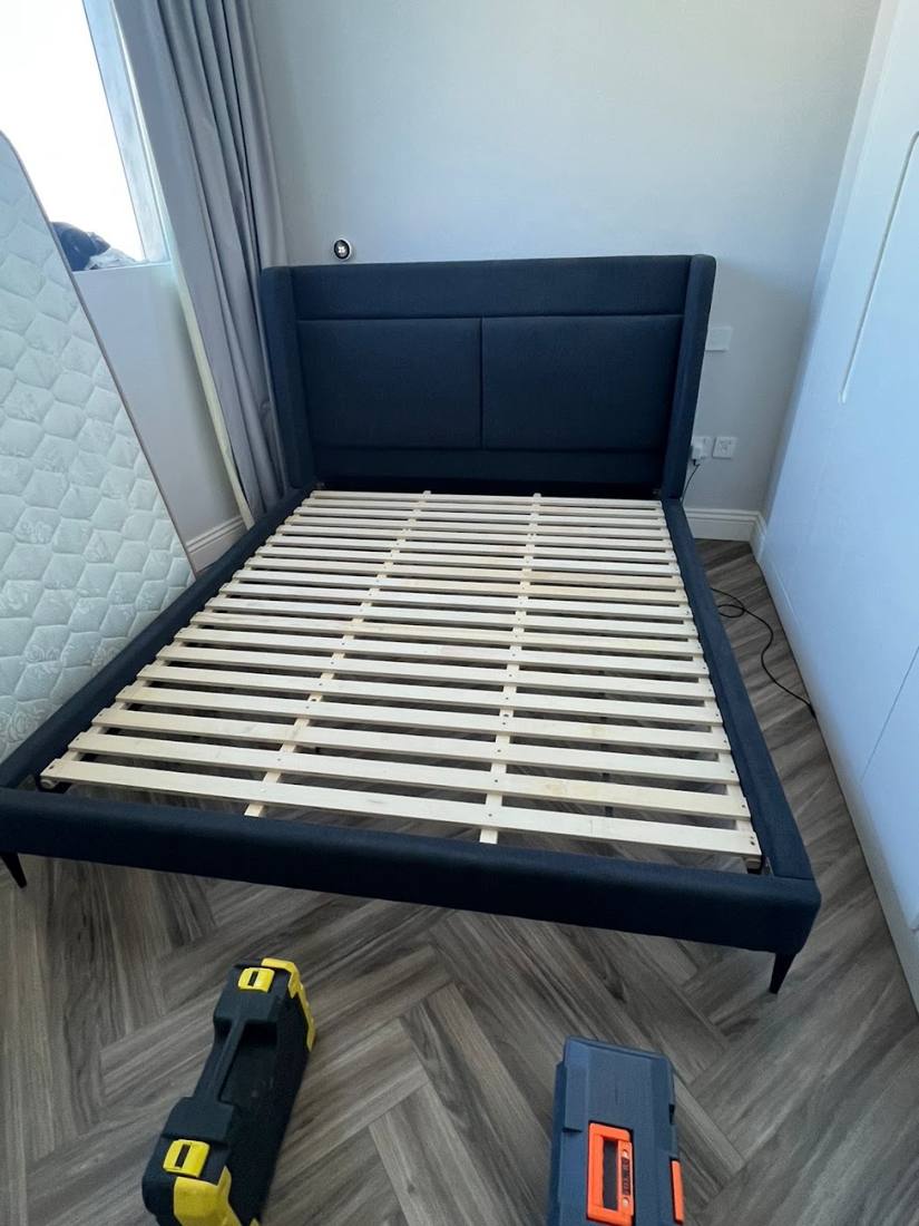 Wooden bed frame being taken apart, with tools